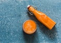 Glass and takeaway bottle with vitamin mango magic smoothies on a blue background, top view. Smoothies with ripe mango, carrot,