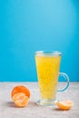 Glass of tangerine orange colored drink with basil seeds on a gray and blue background. Side view Royalty Free Stock Photo