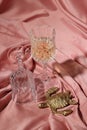 Glass of tasty alcoholic drink, empty one and golden decorative turtle on color fabric