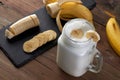 glass of tasty banana smoothie with sliced bananas