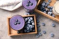 Glass of tasty blueberry smoothie and frozen berries in wooden box on table