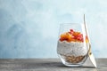 Glass of tasty chia seed pudding with granola, persimmon and pomegranate on table