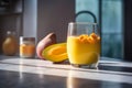 Glass of mango banana smoothie for breakfast on sunny morning in the kitchen