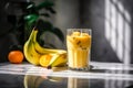 Glass of mango banana smoothie for breakfast on sunny morning in the kitchen