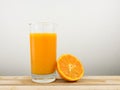 The glass of tasty pure orange juice and fresh orange half on wooden tray Royalty Free Stock Photo