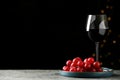 Glass of tasty red wine and fresh grapes on table against dark background with blurred lights. Space for text Royalty Free Stock Photo