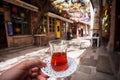 Glass of tea in hand of a visitor of outdoor cafe in a Turkish town. Dinner on street it traditional way in Turkey Royalty Free Stock Photo