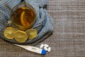 A glass of tea with lemon wrapped in a wool gray scarf. On the table lies a thermometer and pills. Royalty Free Stock Photo