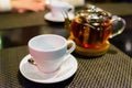 Glass teapot with blooming black tea and white cup table and dark background still life Royalty Free Stock Photo