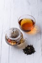 Glass teapot with blooming green tea and cup of tea on white wooden table Royalty Free Stock Photo