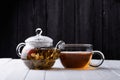 Glass teapot with blooming green tea and cup of tea on white wooden table Royalty Free Stock Photo