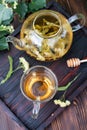 Glass teapot and a cup of linden tea on a dark wooden tray on the table, healthy herbal tea Royalty Free Stock Photo