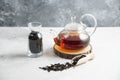 A glass teapot with dried loose teas and a wooden spoon