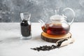 A glass teapot with dried loose teas and a wooden spoon