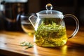 glass teapot filled with steeping green tea leaves