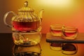 Glass teapot on glass stand heated by candle on yellow background Royalty Free Stock Photo