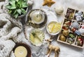 Glass teapot with green tea, flower, candle, knitted plaid and box of christmas decorations on a fluffy carpet on a light Royalty Free Stock Photo