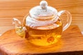 Glass teapot with herbal chamomile tea close-up on wooden board background Royalty Free Stock Photo