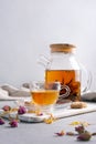 Glass teapot of hot fragrant craft blossom tea with cup and dry rose bud, sugar Royalty Free Stock Photo