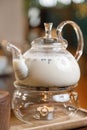 Glass teapot with milk tea on the bar. Tea served by candlelight close-up.