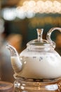 Glass teapot with milk tea on the bar. Tea served by candlelight close-up.