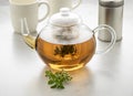 Glass teapot with oregano tea and a fresh twig of oregano