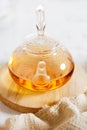 Glass teapot with steam on wooden plate