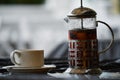 Glass teapot with tea and cup on a table in a street cafe in the rain. Raindrops falling on the table. Royalty Free Stock Photo