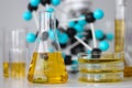 Glass test tubes with yellow viscous liquid stand on table in chemical laboratory closeup