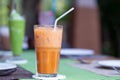 A glass of Thai iced tea with white straw put on dining table with green tea in a restaurant background. Royalty Free Stock Photo