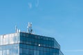 A glass tiled building with an antenna on the roof top of it against a clear blue sky Royalty Free Stock Photo