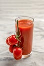 A glass of tomato juice and a branch of small tomatoes banner. Cherry tomatoes in a red plate on a marble background Royalty Free Stock Photo