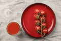 A glass of tomato juice and a branch of small tomatoes banner. Cherry tomatoes in a red plate on a marble background Royalty Free Stock Photo