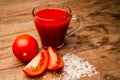 Glass with tomato juice and ripe tomatoes on a wooden table Royalty Free Stock Photo