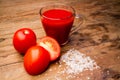Glass with tomato juice and ripe tomatoes on a wooden table Royalty Free Stock Photo