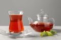Glass of traditional Turkish tea and pot on light grey table, closeup Royalty Free Stock Photo