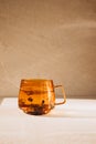 Glass transparent orange mug with hot green tea, shadow and reflection on light stone background