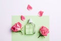 Glass transparent perfume bottle and pink rose flowers on green and white background. Top view, flat lay, mockup Royalty Free Stock Photo