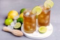 Glass of Tsasty Ice Tea with Ice Cubes and Citrus Cold Summ er Beverage Wooden Squeezer and Raw Lemons and Limes on Background