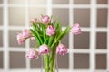 Glass vase with a bouquet of beautiful purple tulips against the background of a stained glass window. Royalty Free Stock Photo