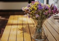 Glass vase with bright beautiful dried flowers on a wooden table in street cafe Royalty Free Stock Photo