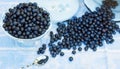 A glass vase full of fresh forest blueberry on the background of berries pouring out of the milk can Royalty Free Stock Photo