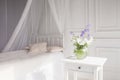 Glass vase with lilac and white floweers  in light cozy bedroom interior. White wall, sunlight from window, copy space Royalty Free Stock Photo