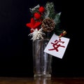 A glass vase with a pine cone inside, some fir branches and red decorations, has a card with Chinese writing which means serenity Royalty Free Stock Photo
