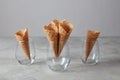 Sweet wafer cones for dessert empty in a glasses on a light gray background. Royalty Free Stock Photo