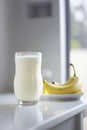 Glass with vegan banana milk with almonds on a white table.Generative AI