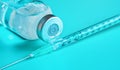 Glass vial with clear liquid and hypodermic syringe needle near, close-up detail cyan background Royalty Free Stock Photo