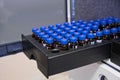 Glass vials with blue caps are in the rack of HPLC system with autosampler. Separation of compounds at chemical or