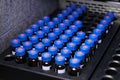 Glass vials with blue caps are in the rack of HPLC system with autosampler. Separation of compounds at chemical or