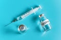 Glass vials with label vaccine and hypodermic syringe needle near, view from above on cyan background Royalty Free Stock Photo